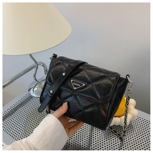 Detail shot of black quilted shoulder bag with silver chain and triangle metal logo plate