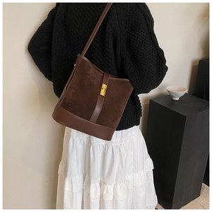 Detail of dark brown faux suede crossbody bag with gold metal buckle on model