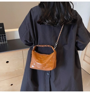 Close-up of brown quilted leather bag with silver chain strap and rivet details