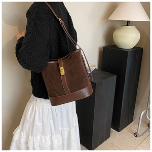 Detail of dark brown faux suede bucket bag with gold lock worn by model
