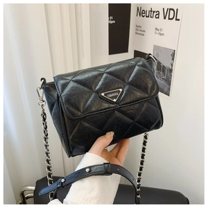 Close-up of quilted black leather texture and silver triangular metal plaque detail