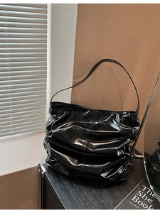 Glossy black ruched shoulder bag with sleek leather finish and minimalist strap design