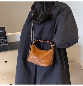 Brown quilted leather shoulder bag with metallic studs and woven handle shown on model
