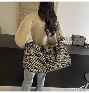 Detail of travel tote bag featuring black and white geometric jacquard and leather handles