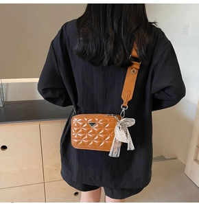 Detailed back view of a brown quilted camera bag with adjustable strap and lace bow charm