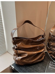 Brown pleated patent leather shoulder bag with glossy finish and modern brand logo
