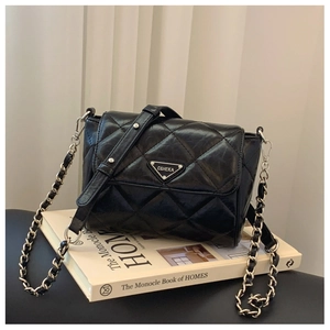 Close-up of black quilted leather crossbody bag with silver triangular logo plate