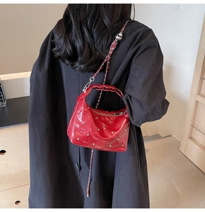 Detail of red patent leather shoulder bag with diamond quilting and silver studs