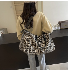 Detail of canvas travel tote bag with black geometric pattern and leather straps
