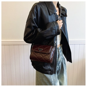 Detailed side view of a brown quilted leather crossbody bag with silver chain strap