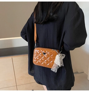 Caramel quilted soft leather camera bag with pearl charm shown on a fashion model