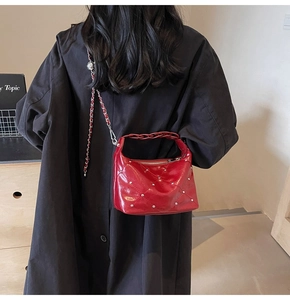 Detail of red quilted leather bag with silver studs and chain strap on a model
