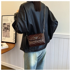 Detail of vintage brown quilted leather crossbody bag with silver chain and metal logo