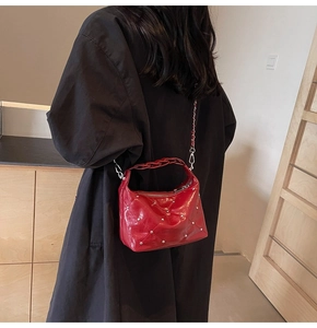 Detail of red quilted hobo bag with silver studs and chain strap shown on model