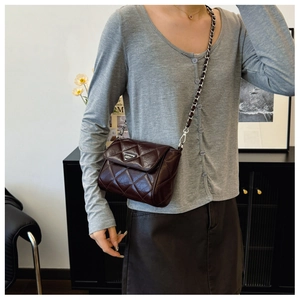 Detail of coffee quilted crossbody bag with metal triangle logo and chain strap