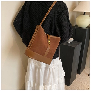 Detail of brown faux suede bucket bag with gold square metal buckle and smooth leather trim