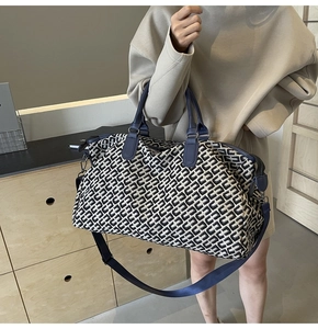 Black and white geometric travel tote with navy leather handles and shoulder strap