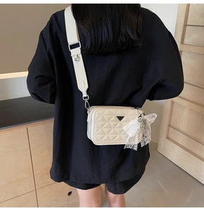 Detail shot of a quilted camera bag with soft cream faux leather and a wide strap