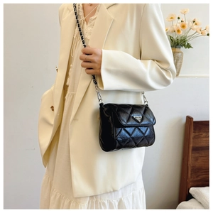 Close-up of quilted black crossbody bag featuring silver triangle logo and chain strap