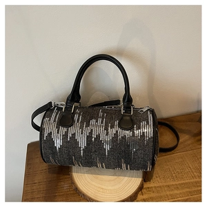 Detail of grey denim boston bag featuring silver sequins and black leather handles