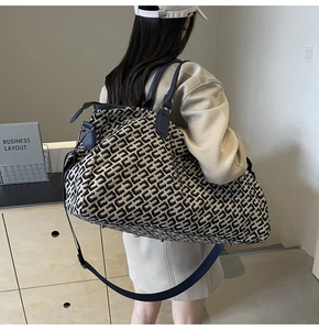Detail of travel tote bag with black and white geometric jacquard pattern and blue strap