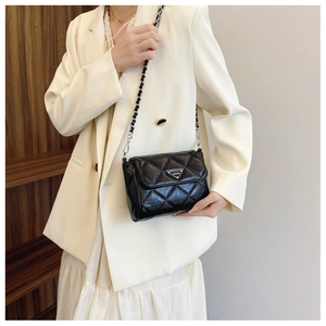 Close-up of black quilted shoulder bag with silver chain and metal triangle hardware