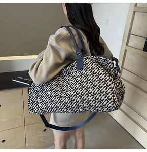 Macro detail of high-capacity travel tote featuring geometric jacquard fabric and leather handles