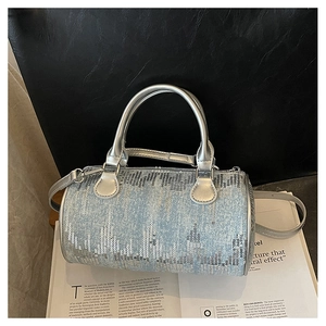Detail of light blue denim cylinder bag with silver sequins on an open magazine