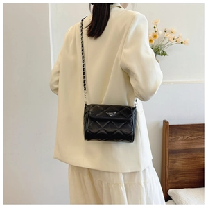 Detail of black quilted chain bag with triangular logo and silver metal strap