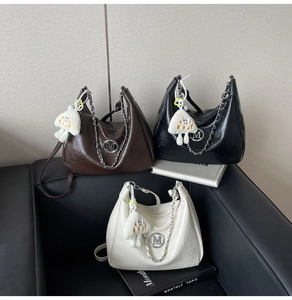 Close-up of pleated leather handbags in brown, black and white with silver M logo charm