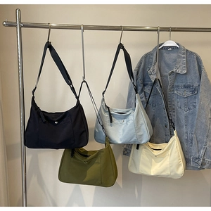 Selezione di quattro borse tote in nylon nero, blu, verde e beige su un supporto