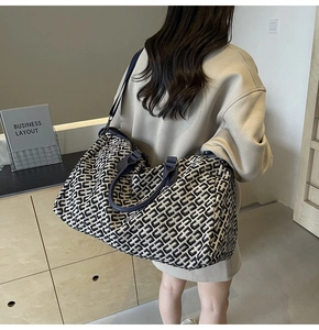 Detail of large travel tote featuring navy blue and beige woven texture with leather straps