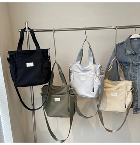 Detailed view of lightweight nylon tote bags in four colors hanging on a metal clothing rack
