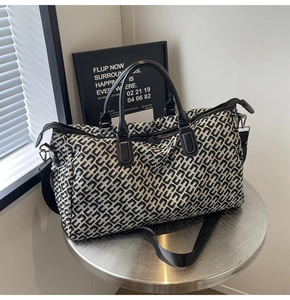Detail of travel tote featuring black and white geometric jacquard fabric and leather handles