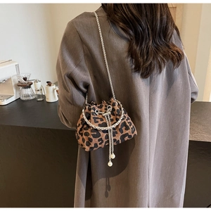 Detail of leopard print bucket bag with rhinestone metal handle and pearl tassel accents