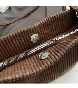 Detailed close-up of dark brown leather tote bag with silver zipper and metallic magnetic snap