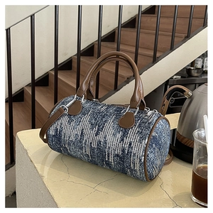 Close-up of denim cylinder bag with white sequins and brown leather trim detailing
