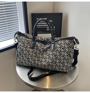 Close-up of geometric pattern travel bag with black leather handles and zipper details