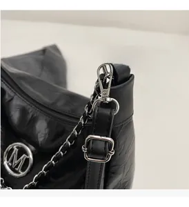 Detail of glossy black pleated tote with silver M logo and metallic chain strap