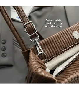 Detail of brown pleated tote bag featuring silver detachable hook and herringbone lining