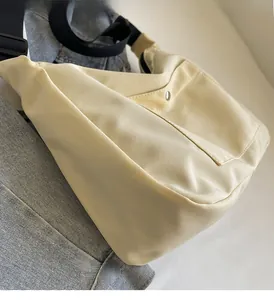 Dettaglio borsa tote in nylon beige con tracolla nera regolabile e tasca con bottone