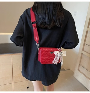 Detail view of red quilted leather camera bag with pearl chain and bow accessory