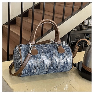 Detail of blue denim pillow bag featuring shimmering silver sequins and brown leather handles
