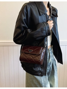 Deep brown quilted chain bag in oil-wax leather with elegant metal triangle detail