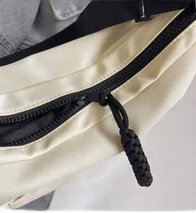 Dettaglio di cerniera nera con tirante in corda su borsa tote in nylon beige