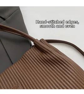 Detail of hand-stitched leather edging and pleated texture on brown shoulder bag
