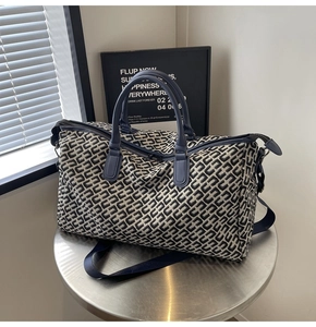 Detail of blue geometric canvas travel bag with navy leather handles and sturdy zipper