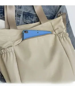 Detail view of the secure back zipper pocket on a beige nylon crossbody bag holding a tablet