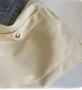Dettaglio della borsa tote in nylon crema con fibbia in metallo argento e tessuto liscio