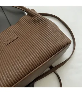 Close-up of brown pleated faux leather tote bag texture and fashion leather label detail
